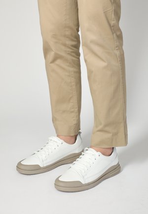 Hvide lædersneakers med lav profil, gummibezige sål og grå accenter. Snørebånd, der er bundet, og syning detaljer på siderne.