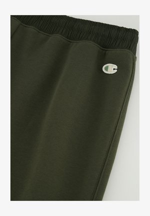 Pantalones deportivos de color verde oscuro con cintura elástica, tejido texturizado y un pequeño logo bordado en el muslo izquierdo inferior.