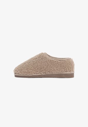 Mocassin beige sans lacets avec une tige en fourrure bouclée douce et une semelle en caoutchouc plate, conçu pour le confort intérieur.