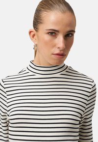 Gestreiftes Top mit hohem Kragen aus weichem Stoff, mit schmalen schwarzen Streifen auf cremefarbenem Hintergrund, in einer figurbetonten Passform.