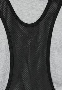 Nahaufnahme eines schwarzen Netzstoff-Panels mit strukturiertem Muster, das einen hellgrauen Stoffhintergrund überlagert.