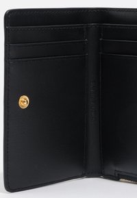 Interior de cartera de piel negra con múltiples compartimentos para tarjetas, acentos en dorado, acabado texturizado y detalle de nombre de marca en relieve.