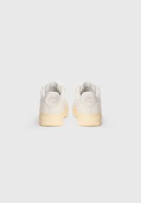Nike Air tenisice u boji slonovače od antilopa i kože, s žutom gumenom petom, teksturiranim stražnjim dijelom i urezanim logotipom na peti.