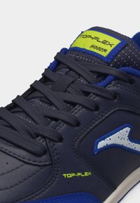 Tumesinised sisespordijalatsid mustade paelte, kollase "TOP-FLEX" logoga ja valge-sinise küljele märgitud väikese logoga.