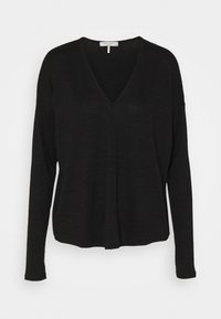 Haut noir à manches longues avec un col en V. Fabriqué à partir d'un tissu doux et léger. Présente une coupe décontractée et des détails de couture subtils au centre.