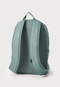 Mochila em azul-turquesa claro, feita de tecido resistente. Possui alças de ombro almofadadas e uma alça superior. Bolsos laterais para armazenamento adicional.