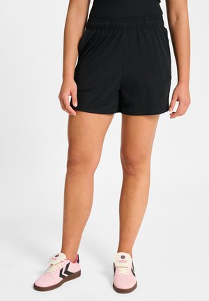 Zwarte sportshorts met elastische tailleband, een gladde textuur en een losse pasvorm, gecombineerd met roze sneakers met zwarte accenten.