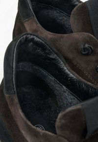Hnědé semišové boty s černými koženými akcenty, s měkkou vnitřní podšívkou a texturovaným povrchem. Diskrétní prošití na bocích.