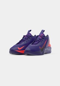 Purple athletic shoes with a textured upper, featuring a vibrant red Nike logo and accents, and a black detail on the lateral side.