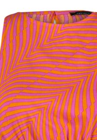Robe colorée présentant un motif géométrique avec des rayures zigzag orange et rose. Le tissu a une texture lisse avec un col rond.