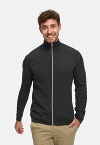 Tmavě šedý svetr na zip s vysokým límcem, zdobený texturovaným vzorem copánkového pletení a kontrastním bílým zipem.