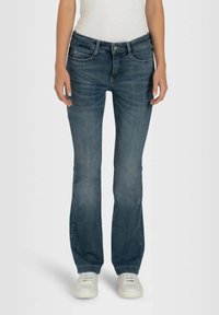 Jeans de denim azul oscuro con un diseño slim fit, cinco bolsillos, cierre de cremallera y costuras en contraste. Presentan una sutil textura descolorida.