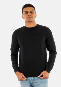 Maglione navy con scollo a giro, maniche lunghe e orlo a costine. Realizzato in un tessuto liscio con una silhouette aderente e un sottile dettaglio di branding.