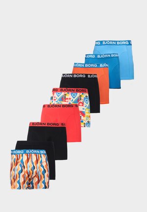 Mandlig model stående barfodet mod en hvid væg iført lyseblå Björn Borg boxershorts, kiggende en smule til siden.