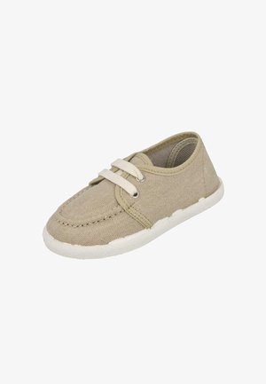Zapato casual de lona beige con suela de goma blanca y dos cordones blancos, diseñado para el uso diario.
