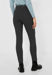 Svart och vitmönstrade leggins med en åtsittande design, elastiskt midjeband och ankellång klippning, kombinerat med svarta ankstövlar.