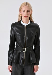 Giacca in finta pelle nera con un corpo aderente, chiusura con zip, orlo a peplum e una cintura con fibbia quadrata. Presenta un colletto alto e una texture liscia.