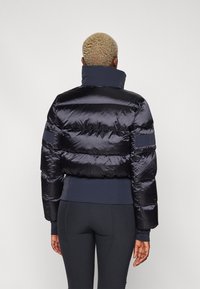 Zwarte pufferjack met een hoge kraag, gestikte ontwerp en elastische manchetten, met een cropped snit en marineblauwe accenten aan de zoom.