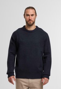 Maglione lavorato a maglia blu navy con colletto e polsini a coste, caratterizzato da una vestibilità rilassata e da una texture morbida. Adatto per un abbigliamento casual.