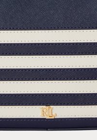 Τσάντα χειρός με navy και κρέμα ρίγες, με υφή και χρυσή λογοτύπηση. Οι οριζόντιες γραμμές δημιουργούν έναν μοντέρνο σχ�εδιασμό.