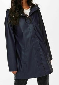 Imperméable marine avec capuche, boutons-pression sur le devant et poches latérales. Caractérisé par une texture lisse et brillante ainsi qu'une coupe décontractée.