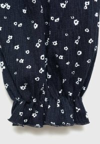 Marinblått tyg med ribbat mönster pryds av små vita blommönster. Ärmslutet är rynkat och har en volangkant.