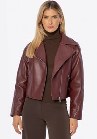 Veste de motard en cuir bordeaux à la coupe courte, avec des revers larges, une fermeture éclair et des poches latérales. Met en valeur une texture lisse.