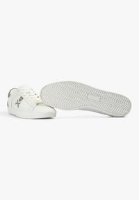 Weiße niedrig geschnittene Sneakers mit einer strukturierten Gummisohle, Logo-Details, gepolsterter Ferse und glattem Lederoberteil. Schnürdesign ohne Muster.