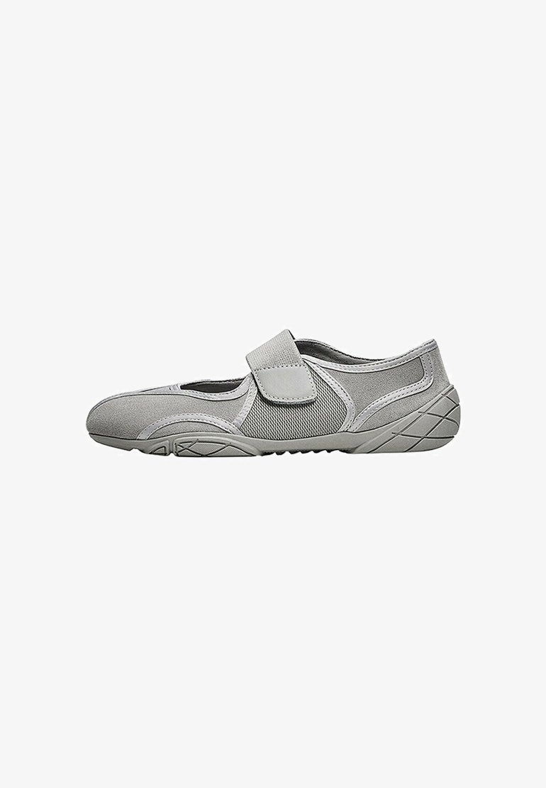 Chaussure de sport gris clair avec des panneaux en mesh, une seule bride velcro et une semelle en caoutchouc texturée vue de profil.