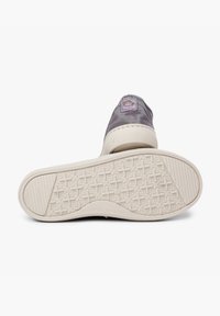 Grijze canvas sneaker met een witte rubberen zool, voorzien van een structuurpatroon aan de onderkant en een label met de tekst "Made in Spain" op de hiel.