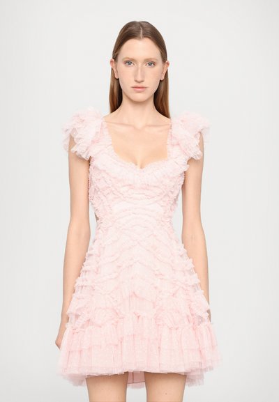 Robe rose clair avec des volants superposés, décolleté carré et manches bouffantes transparentes. Le tissu texturé présente des pois sur toute sa surface.