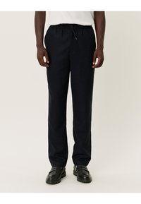 Pantalons de jogging bleu marine en tissu doux, avec une taille élastique dotée d'un cordon de serrage et une coupe droite.