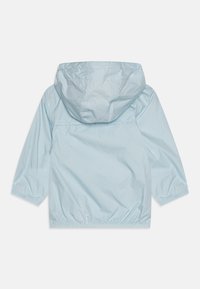 Giacca a vento azzurro chiaro con cappuccio, polsini elasticizzati e orlo elastico. Tessuto liscio e lucido con un design minimalista.