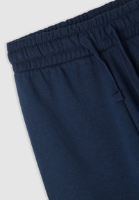 Granatowe dresy z elastycznym paskiem i sznurkiem. Miękka tkanina o gładkiej fakturze, bez widocznych wzorów czy szczegółów metalowych.