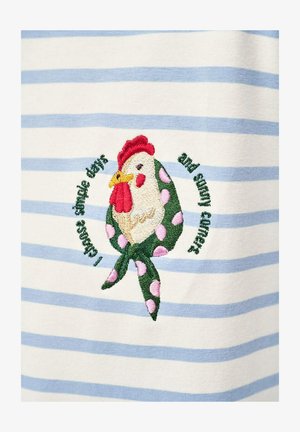 Wyhaftowany kurczak w zielonym szaliku w różowe kropki na białej i jasnoniebieskiej pasiasttej tkaninie, otoczony tekstem ułożonym w okrąg.