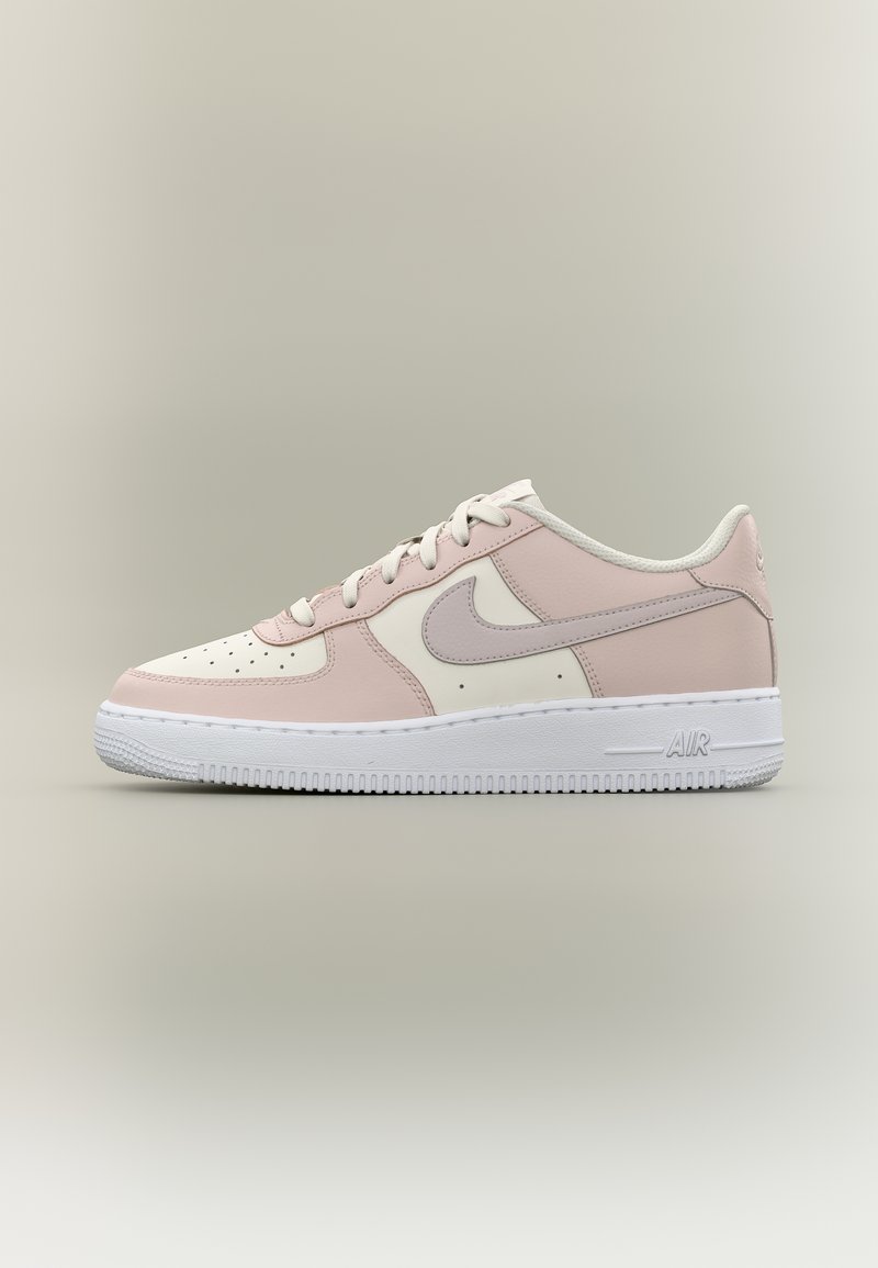 Χαμηλού στυλ αθλητικό παπούτσι Nike Air σε ανοιχτό ροζ, λευκό και μπεζ, με λευκά κορδόνια και λευκή σόλα σε ουδέτερο φόντο.