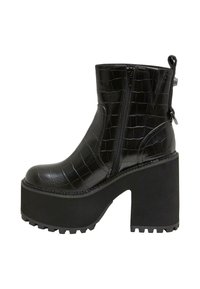 Botas negras hasta el tobillo hechas de cuero sintético con grabado de cocodrilo. Cuentan con una suela de plataforma gruesa, cremallera lateral y un talón reforzado.