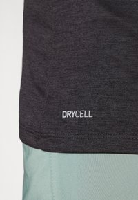 Cămașă sport gri cu o textură netedă și logo-ul DRYCELL la tiv, combinată cu un material verde deschis care are un design simplu.