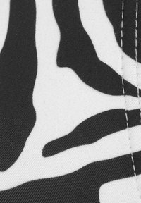 Zwart-witte zebra-print stof met een gladde textuur, met gedurfde, golvende strepen en zichtbare stiksels langs de randen.