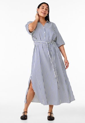 Robe chemise à rayures avec des manches courtes, taille ceinturée et fente latérale. Les couleurs incluent le blanc et le bleu marine. Tissu léger.