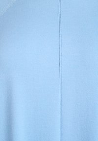 Hele sinine kudumõngas, sileda tekstuuriga ja keskel õmblusega. Materjal paistab olevat elastne ja keha järgiv.