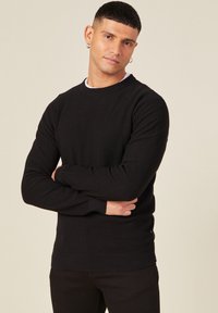 Schwarzer, gerippter Langarmpullover mit Rundhalsausschnitt und enganliegenden Bündchen, ausgestattet mit einem strukturierten Stoff und einem geraden Saum.