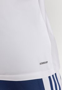 White athletic shirt featuring the "AEROREADY" label. The fabric is smooth and stretchy, with a curved hem and simple design.