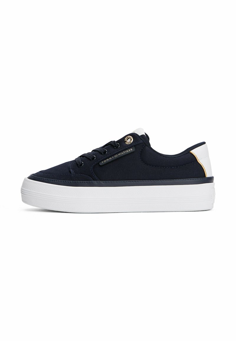 Sneaker in tela blu navy con suola in gomma bianca, dettagli oro e occhielli. Presenta un design con lacci e un dettaglio con logo sul lato. Forma a profilo basso.
