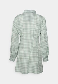 Vestido de camisa xadrez verde e branco, mangas longas, colarinho, ajustado ao corpo, punhos com botão, comprimento médio, tecido suave com textura lisa.