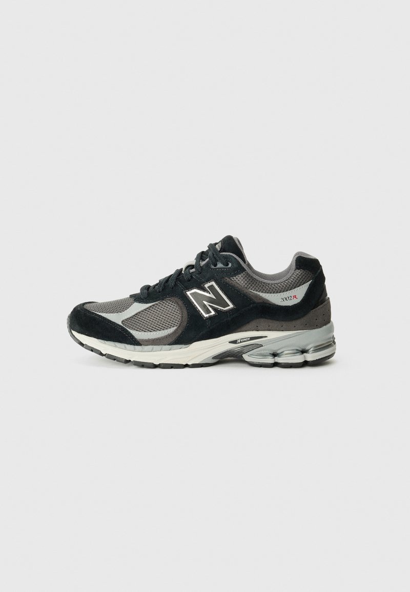 Baskets New Balance 2002R noires et grises avec panneaux en mesh et en suède, fermeture à lacets à l'avant et semelle coussinée avec absorbeurs de chocs visibles.