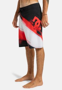 Čierne a červené plážové kraťasy s bielym dizajnom, obsahujúce grafický vzor a šnúrku v páse. Vyrobené z ľahkého, rýchloschnúceho materiálu.