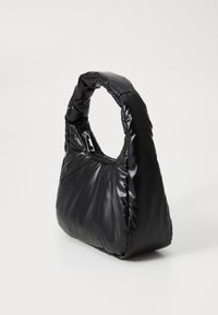 Sac à main noir rembourré avec une poignée arrondie et une fermeture éclair. Il présente une texture lisse et brillante et a une forme triangulaire.