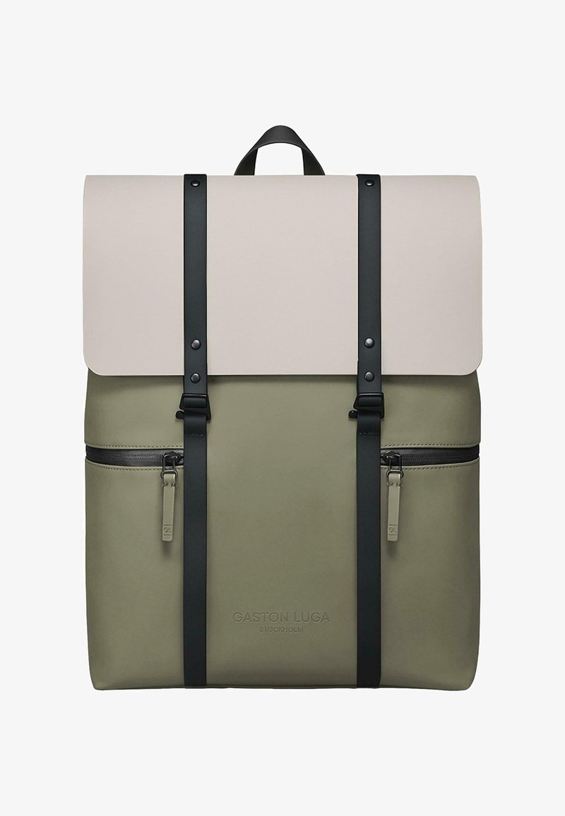 Rucksack in Olivgrün mit einer cremefarbenen Klappe, ausgestattet mit schwarzen Trägern und Reißverschlüssen. Enthält ein Logodetail auf der Vorderseite. Glatte Textur.