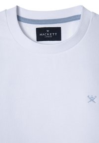 T-shirt bianca in cotone con collo a giro, caratterizzata da un accento azzurro chiaro nel colletto e un piccolo logo ricamato blu sul petto.